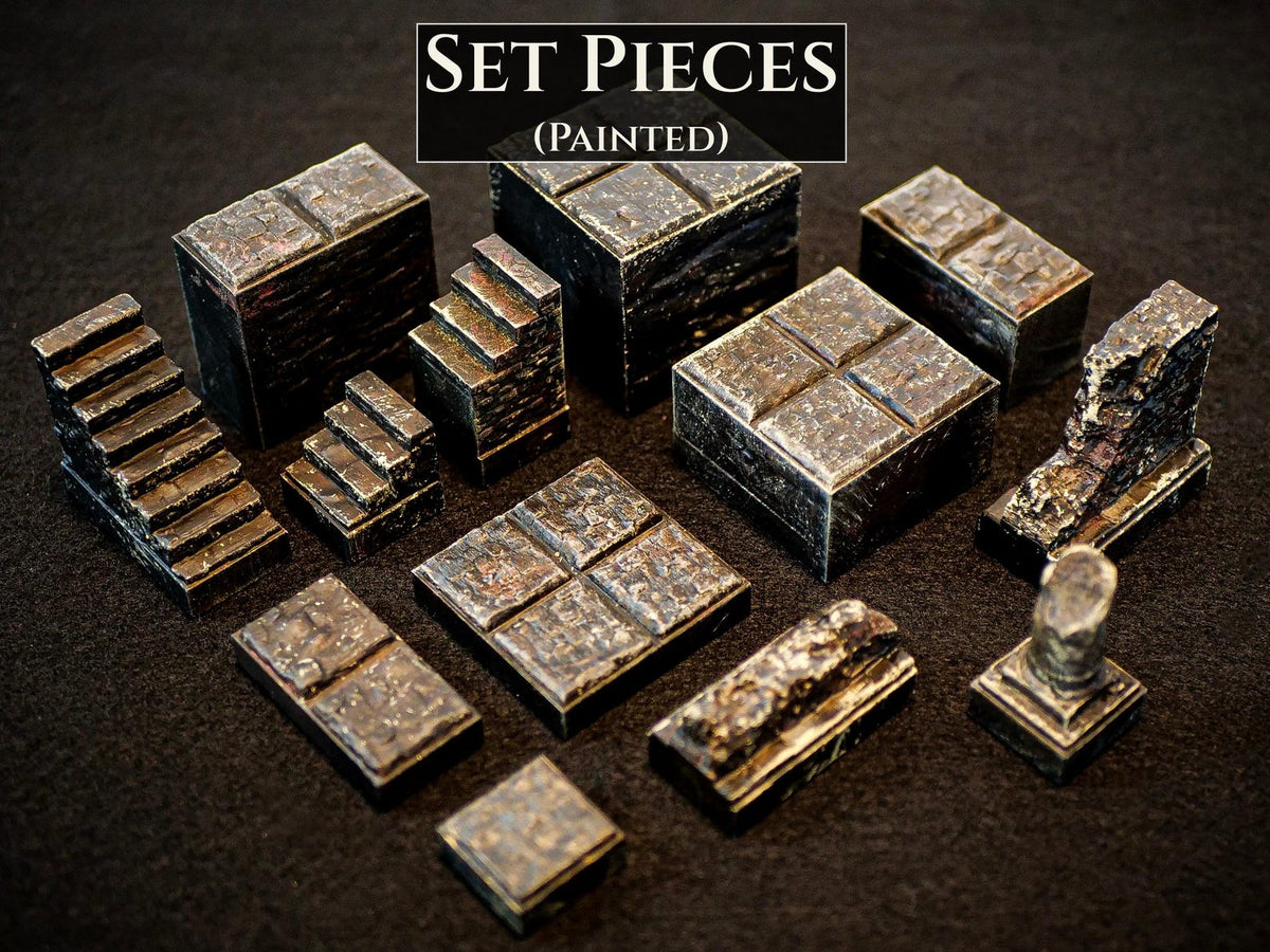 A collection of painted miniature terrain set pieces featuring stone-like textures in dark gray and brown tones. The set includes various block shapes, stairs, a square platform, a broken wall section, and a small pillar. Text reads SET PIECES (PAINTED).