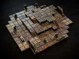 A multi-level dungeon terrain tile set featuring a grid of square stone blocks with a weathered, dark brown and metallic finish. The structure includes raised platforms, small staircases, and broken pillar fragments arranged in a layout.