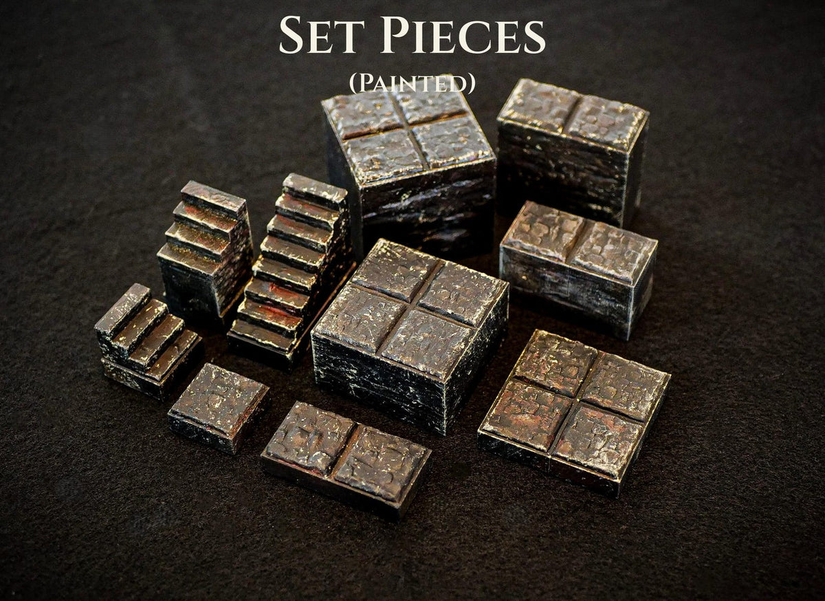 A collection of painted miniature set pieces featuring dark, weathered stone textures. The items include square blocks, rectangular platforms, and small staircases, all with a rugged, aged appearance. The text SET PIECES (PAINTED) is visible.