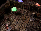 A tabletop gaming dungeon terrain set featuring a dark stone grid floor with textured walls, a glowing green fire brazier, and two miniature figurines standing on clear circular bases within the modular stone room environment.
