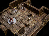 A miniature dungeon terrain set featuring dark brown, weathered stone floor tiles with a grid pattern and raised walls. Several small, painted character figurines stand on clear circular bases, positioned across the multi-level stone structure.