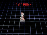 A miniature 1x1 inch pillar with a weathered, dark, and reddish-brown textured finish. The object features a square base and a cylindrical top section, presented on a black grid surface with the text 1x1 inch Pillar visible.