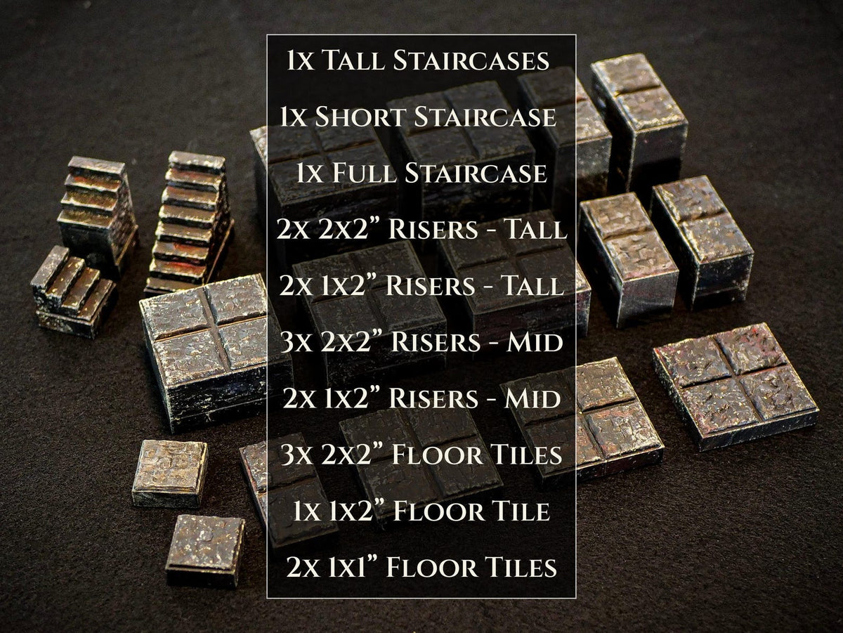 A collection of dark gray stone-textured gaming terrain pieces including staircases, risers, and floor tiles. The text lists: 1x Tall Staircases, 1x Short Staircase, 1x Full Staircase, 2x 2x2" Risers - Tall, 2x 1x2" Risers - Tall, 3x 2x2" Risers - Mid, 2x 1x2" Risers - Mid, 3x 2x2" Floor Tiles, 1x 1x2" Floor Tile, 2x 1x1" Floor Tiles.