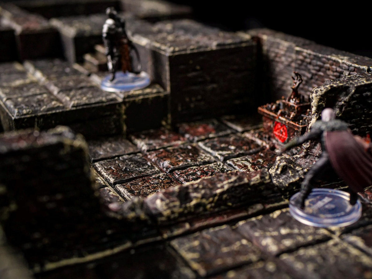 A detailed tabletop gaming scene featuring a dungeon setting with stone tiles and miniature figures. The environment is dark and textured, with a focus on the game's immersive design. The figures are in action poses, enhancing the game's narrative.