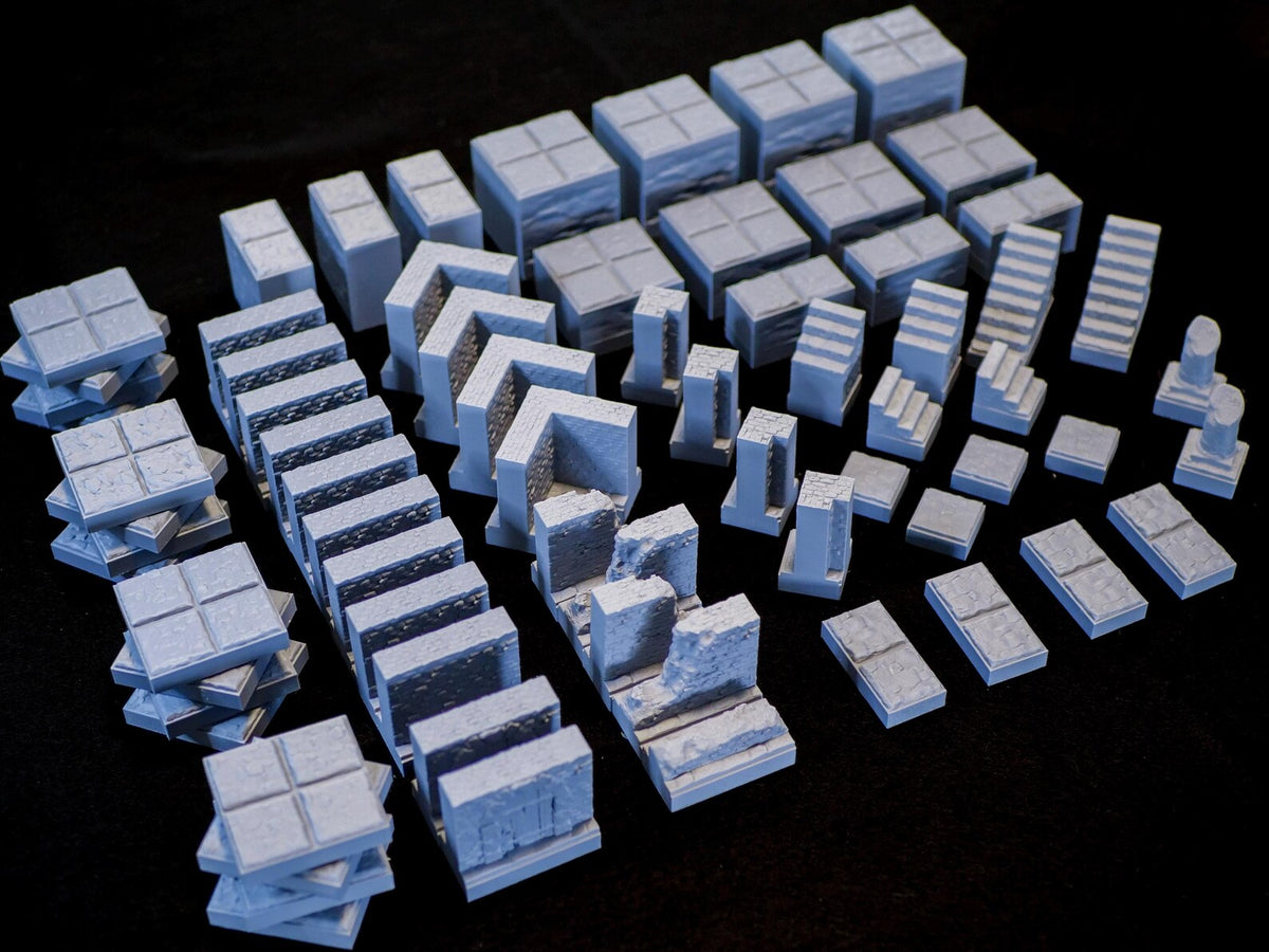 A collection of light blue miniature dungeon terrain pieces, including square floor tiles with grid patterns, various wall segments with stone textures, staircases, and pillar components, all designed for tabletop gaming setups.