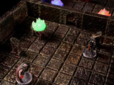A tabletop gaming dungeon terrain set featuring a dark stone grid floor with textured walls, a glowing green fire brazier, and two miniature figurines standing on clear circular bases within the modular stone room environment.