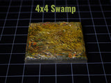 A square 4x4 Swamp terrain tile featuring a textured, uneven surface painted in shades of dark green, brown, and ochre with subtle red highlights. The piece has a glossy finish and is displayed against a black grid background.