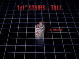 A miniature staircase model with a weathered brick texture in shades of gray and red. The piece features the text 1x1 STAIRS - TALL and 2 HEIGHT, indicating a 2-inch height measurement for the structure on a black grid surface.