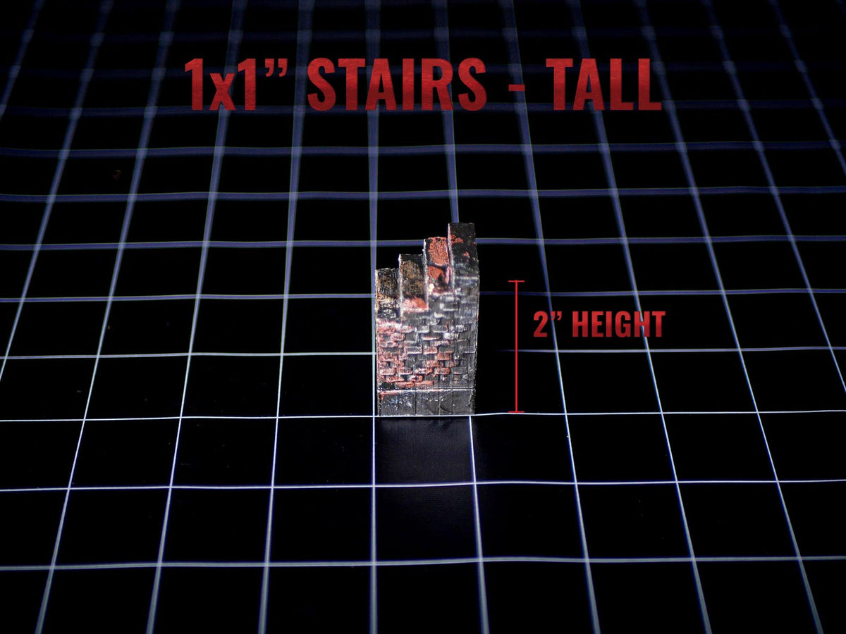 A miniature staircase model with a weathered brick texture in shades of gray and red. The piece features the text 1x1 STAIRS - TALL and 2 HEIGHT, indicating a 2-inch height measurement for the structure on a black grid surface.