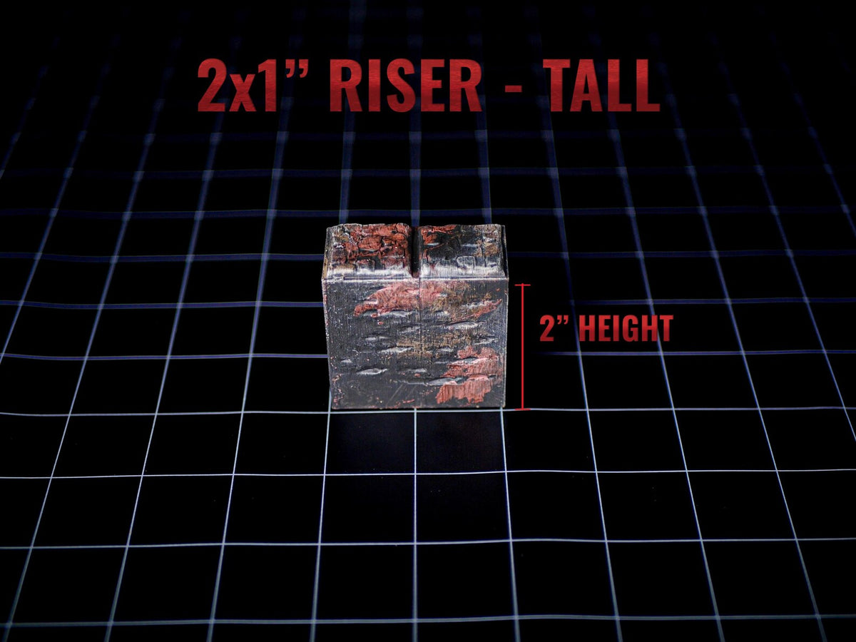 A rectangular riser block with a dark, weathered finish featuring patches of reddish-brown texture. The top surface has a narrow slit. Text on the image reads 2x1" RISER - TALL and 2" HEIGHT, indicating a height of 2 inches.